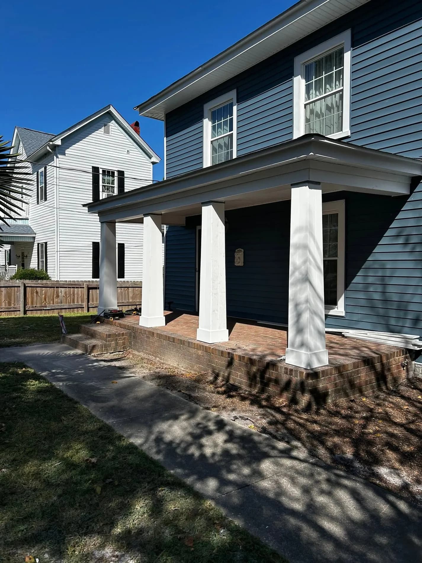 Two-storey home finished by FFC in deep blue siding, with square white porch columns and white trim.
